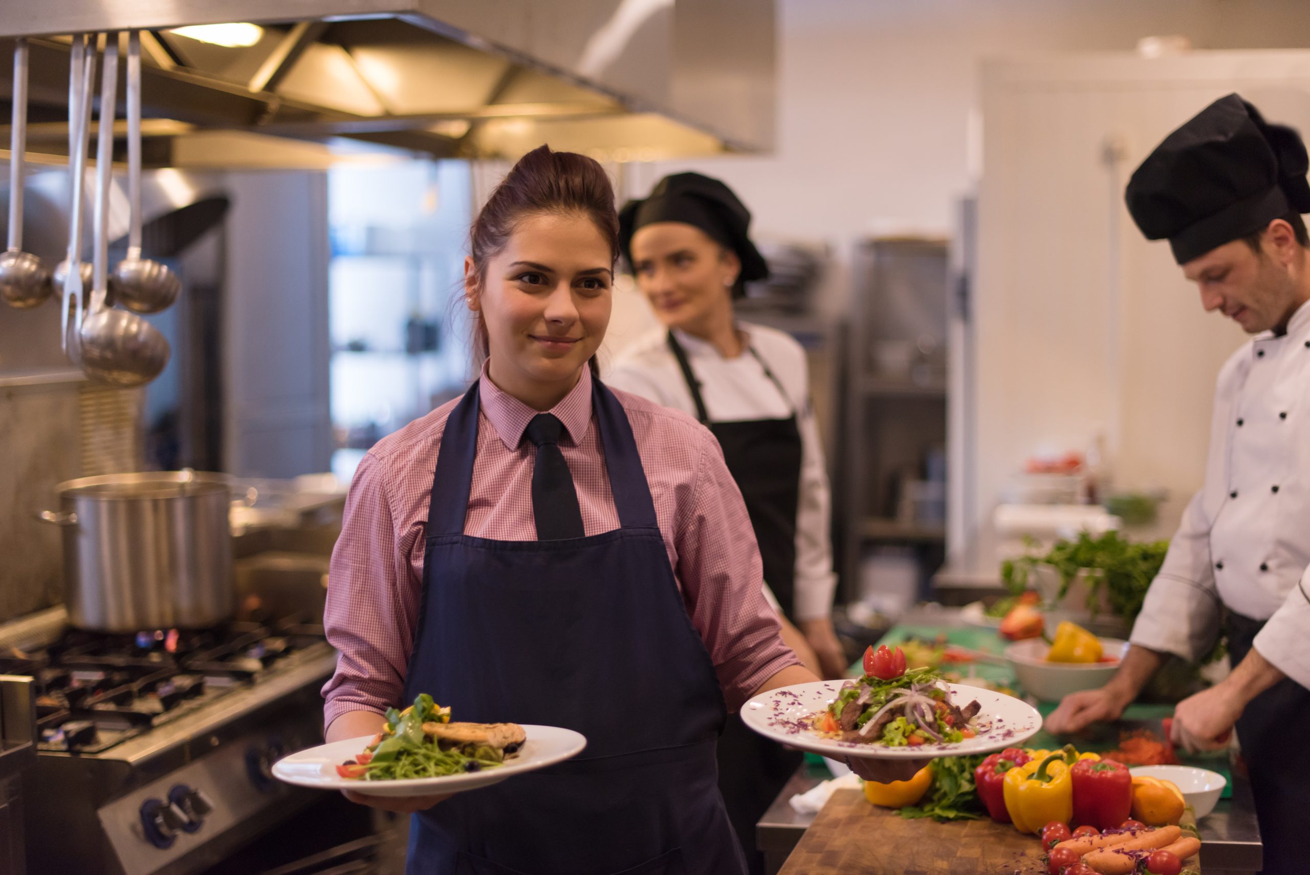 young waitress showing dishes of tasty meals 5 Valuable Soft Skills Every Hotel Management Student Should Master